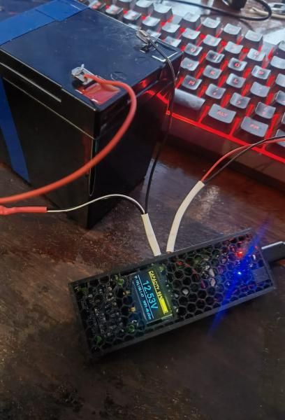 The finished monitor in its honeycomb-lid enclosure, wired to a small 12 V battery on a workbench