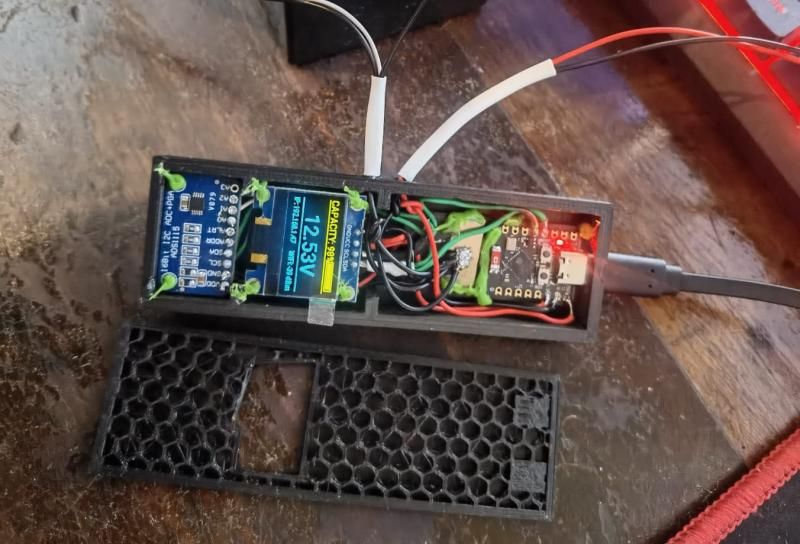 Open enclosure: the OLED and ADS1115 board in one compartment, the ESP32-C3 and wiring glued in the other, honeycomb lid beside it