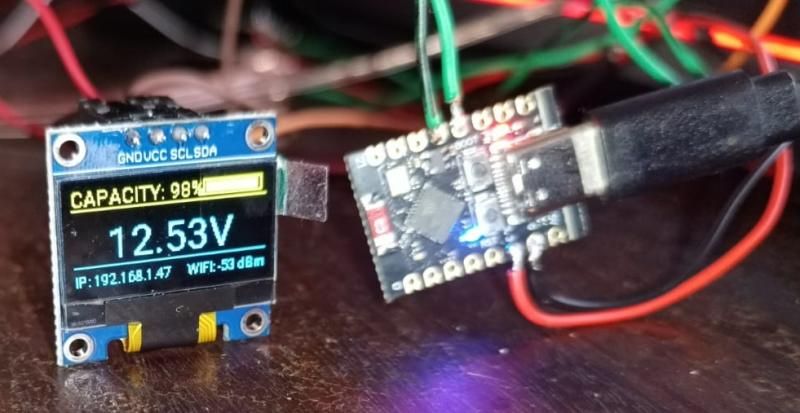 Loose OLED module showing 12.53 V next to a tiny ESP32-C3 board on USB-C, during early testing