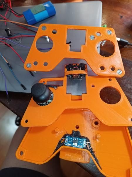 The remote taken apart into its stacked orange panels, with the joystick and boards visible between the layers