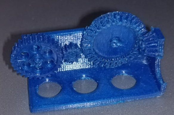 A blue 3D-printed gear train on a test base, with visibly rough teeth