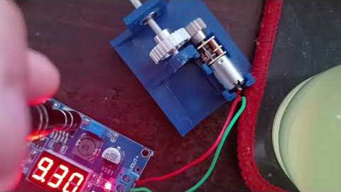 The N20 motor turning white gears on a blue 3D-printed test mount, powered from a bench supply